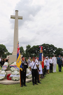 Britse en Franse militairen tijdens fotomomenten bij het stenen kruis met kransen