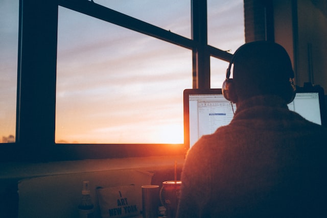 Man working behind laptop with sunset